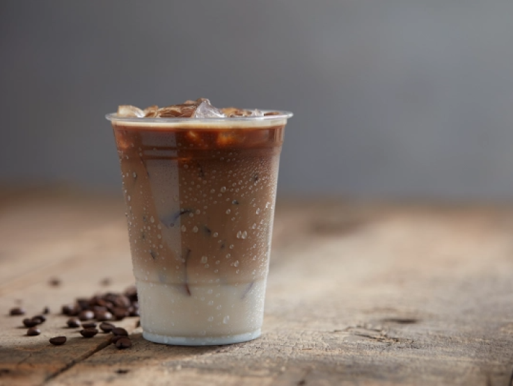 Iced coffee filled with ice cubes and creamy milk, served in a clear glass.